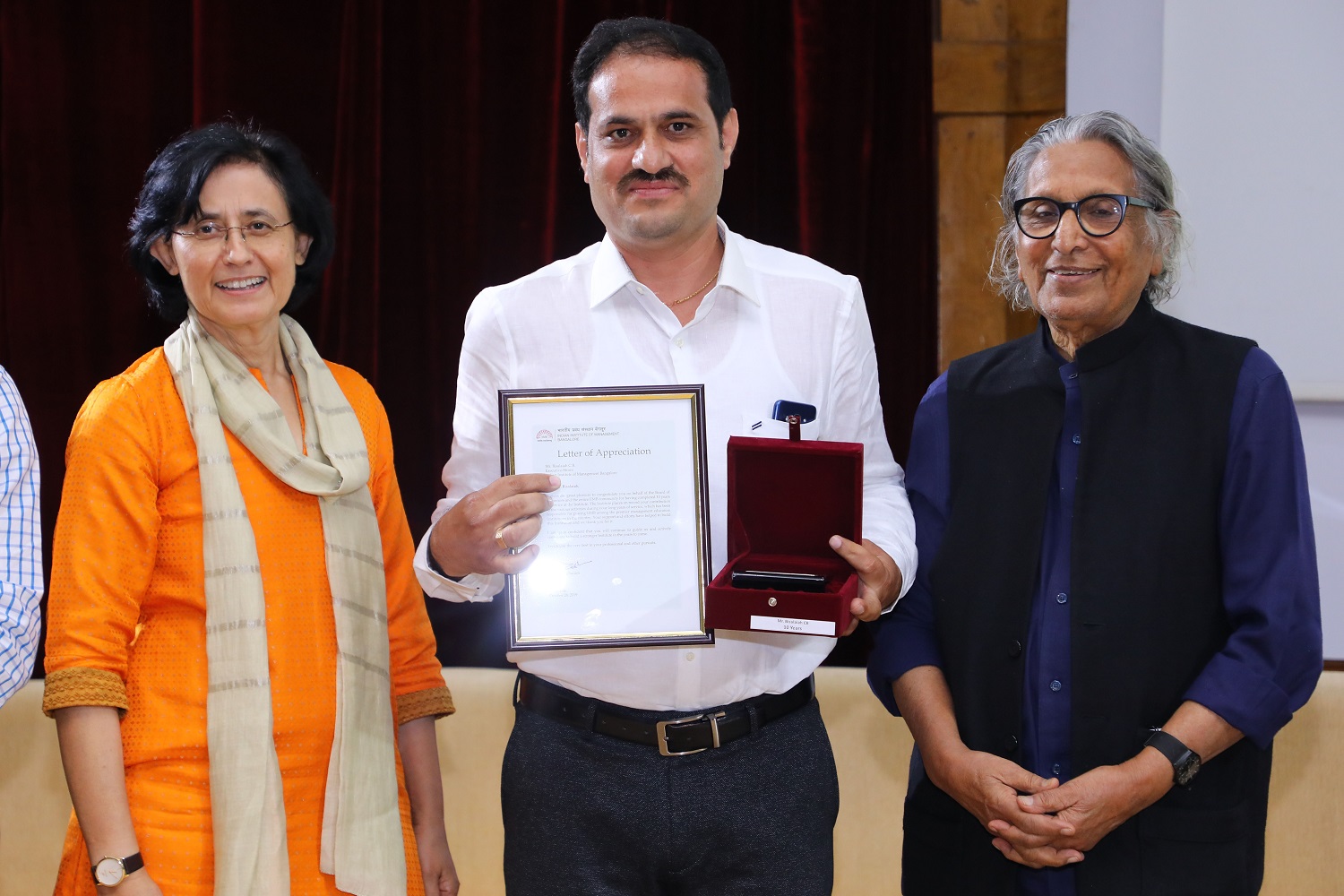 Bisilaiah C.B., Executive, Stores Department, receives 10 years’ Service award from Ms. Vinita Bali, Member, Board of Governors, IIMB, and Pritzker Laureate Dr. Balkrishna Doshi, on the occasion of IIMB’s 46th Foundation Day celebrations.