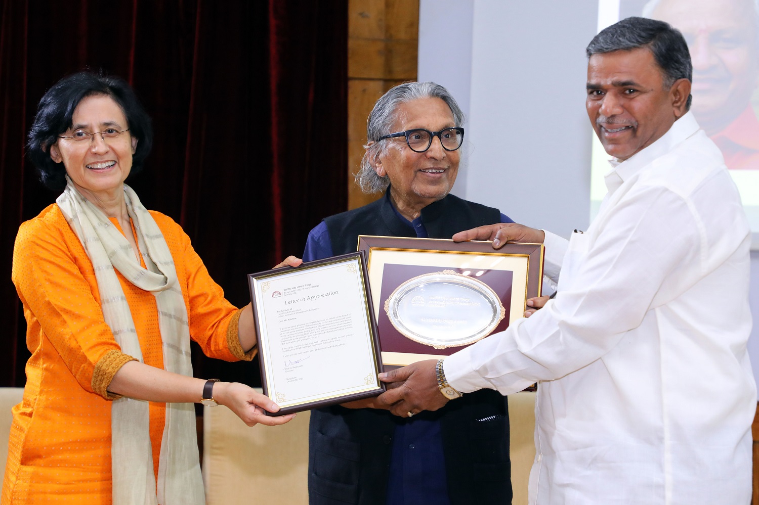 Ramakrishna K., Junior Office Assistant, receives 40 years’ Service award from Ms. Vinita Bali, Member, Board of Governors, IIMB, and Pritzker Laureate Dr. Balkrishna Doshi, on the occasion of IIMB’s 46th Foundation Day celebrations.
