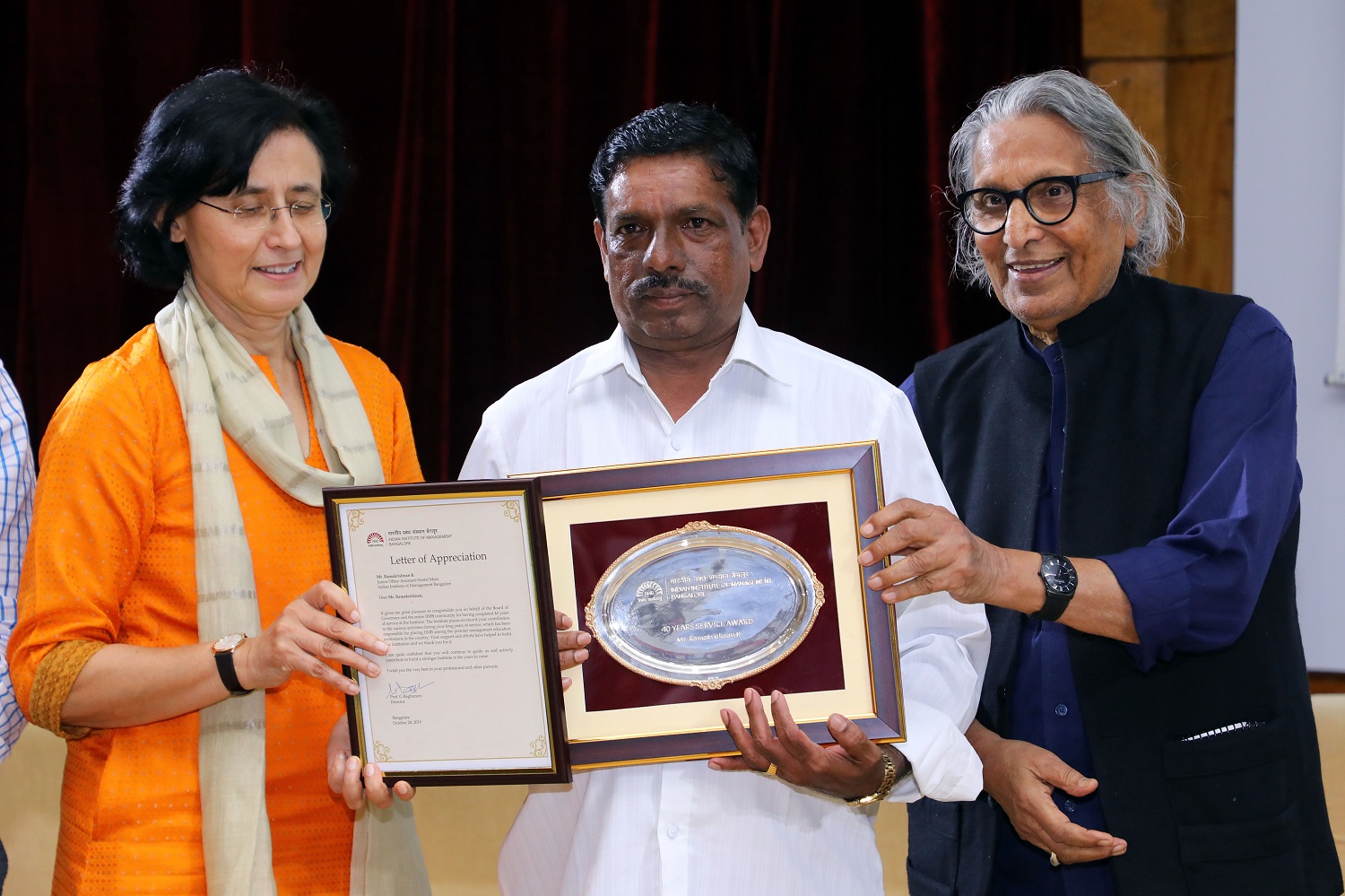 Krishna M., Head Cook, Hostels, receives 40 years’ Service award from Ms. Vinita Bali, Member, Board of Governors, IIMB, and Pritzker Laureate Dr. Balkrishna Doshi, on the occasion of IIMB’s 46th Foundation Day celebrations.