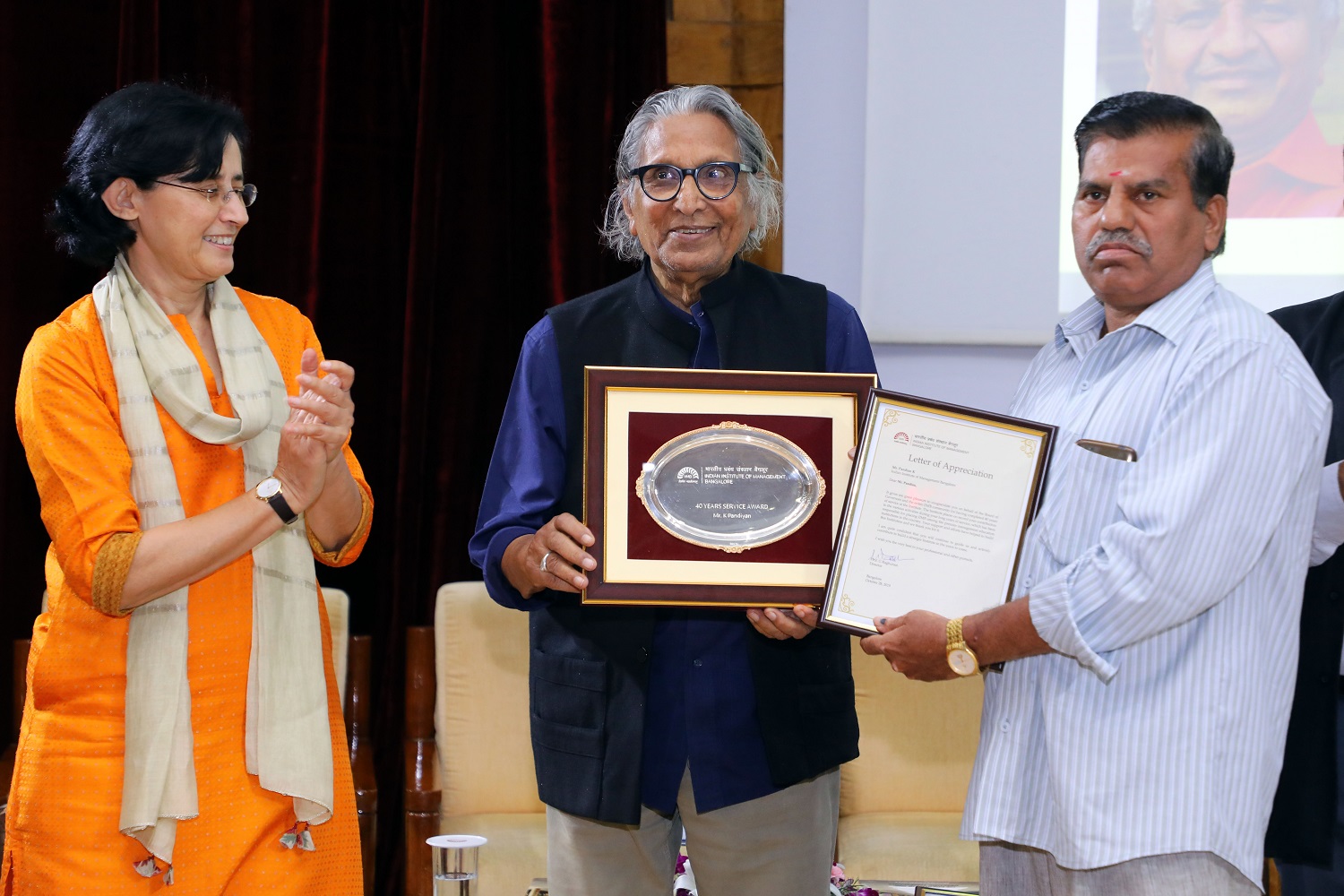 Pandian K., Head Cook, receives 40 years’ Service award from Ms. Vinita Bali, Member, Board of Governors, IIMB, and Pritzker Laureate Dr. Balkrishna Doshi, on the occasion of IIMB’s 46th Foundation Day celebrations.