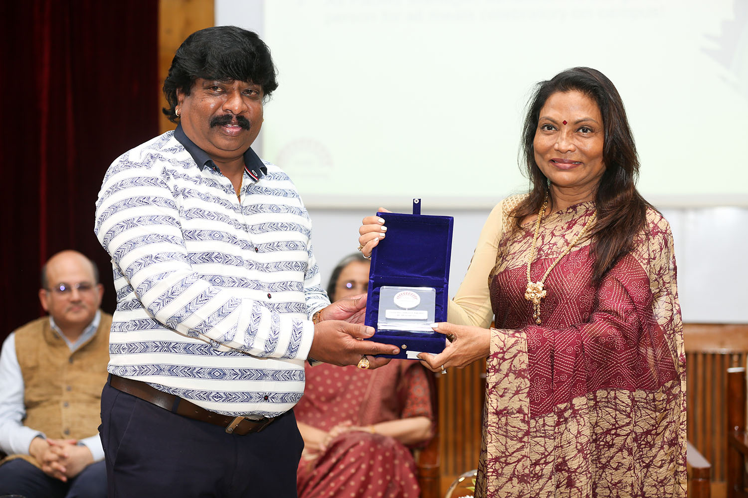 Mr M Janakiram, Facility Manager, receives the award for 10 years of service from Ms. Kalpana Saroj, Member of the Board of Governors, IIMB, during the institute’s 49th Foundation Day celebrations.