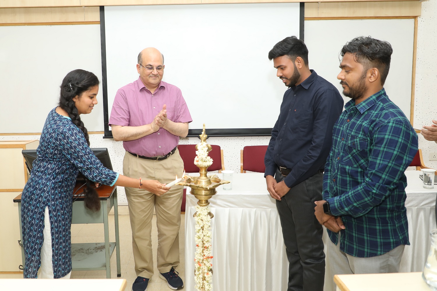 A Pre-doctoral student lights the lamp at the inauguration. IIMB, Prof. Rishikesha T Krishnan, Director, IIMB, applaud.