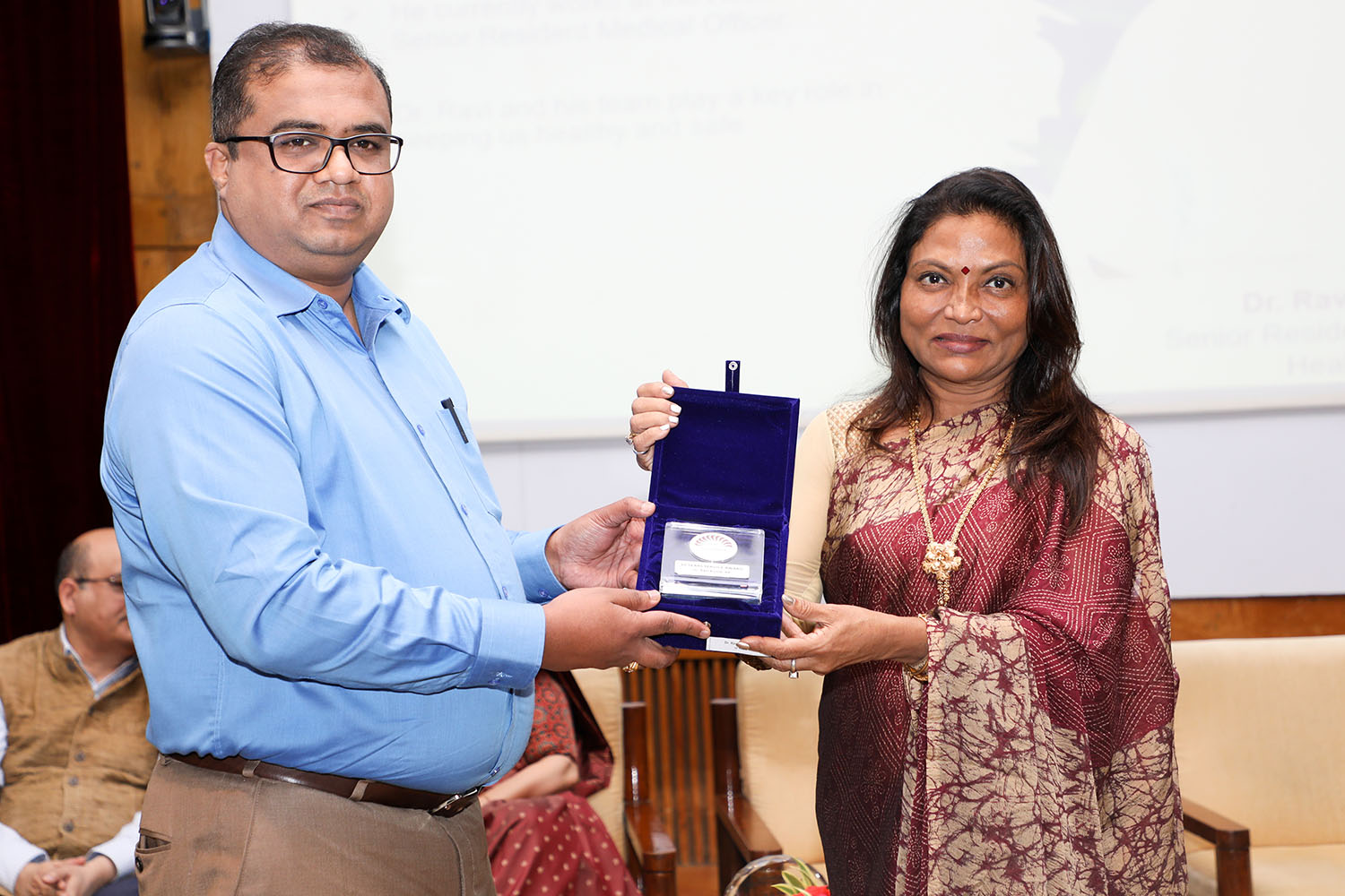 Dr. Ravi Kumar KR, Senior Resident Medical Officer, receives the award for 10 years of service from Ms. Kalpana Saroj, Member of the Board of Governors, IIMB, during the institute’s 49th Foundation Day celebrations.