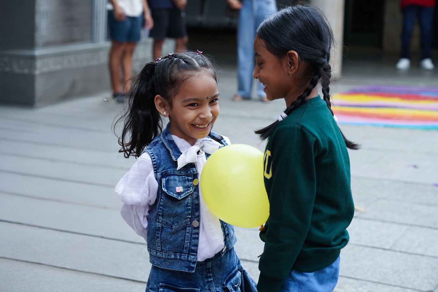Two young participants share a moment of laughter during a fun balloon game.