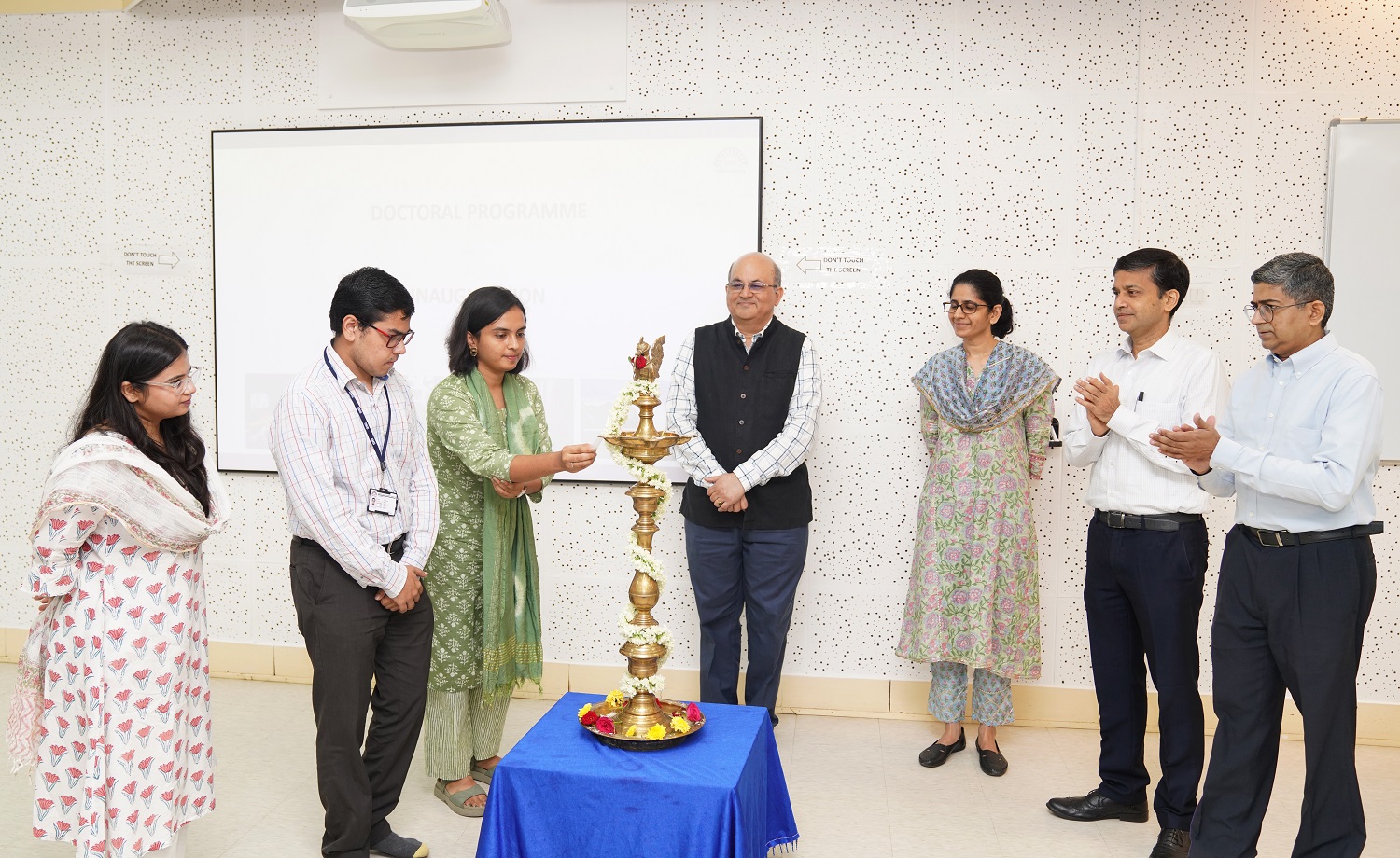 A PhD student from the class of 2024 lights the ceremonial lamp at the inauguration on 10th June 2024. Prof. Rishikesha T Krishnan, Director, IIMB, Prof. Mukta Kulkarni, faculty in the OB&HRM area and Dean of Academic Programs at IIMB, Prof. Sourav Mukherji, faculty in the OB&HRM area and Dean of Alumni Relations and Development, IIMB and Prof. Ananth Krishnamurthy, Chairperson, PhD Programme, IIMB, applaud. 