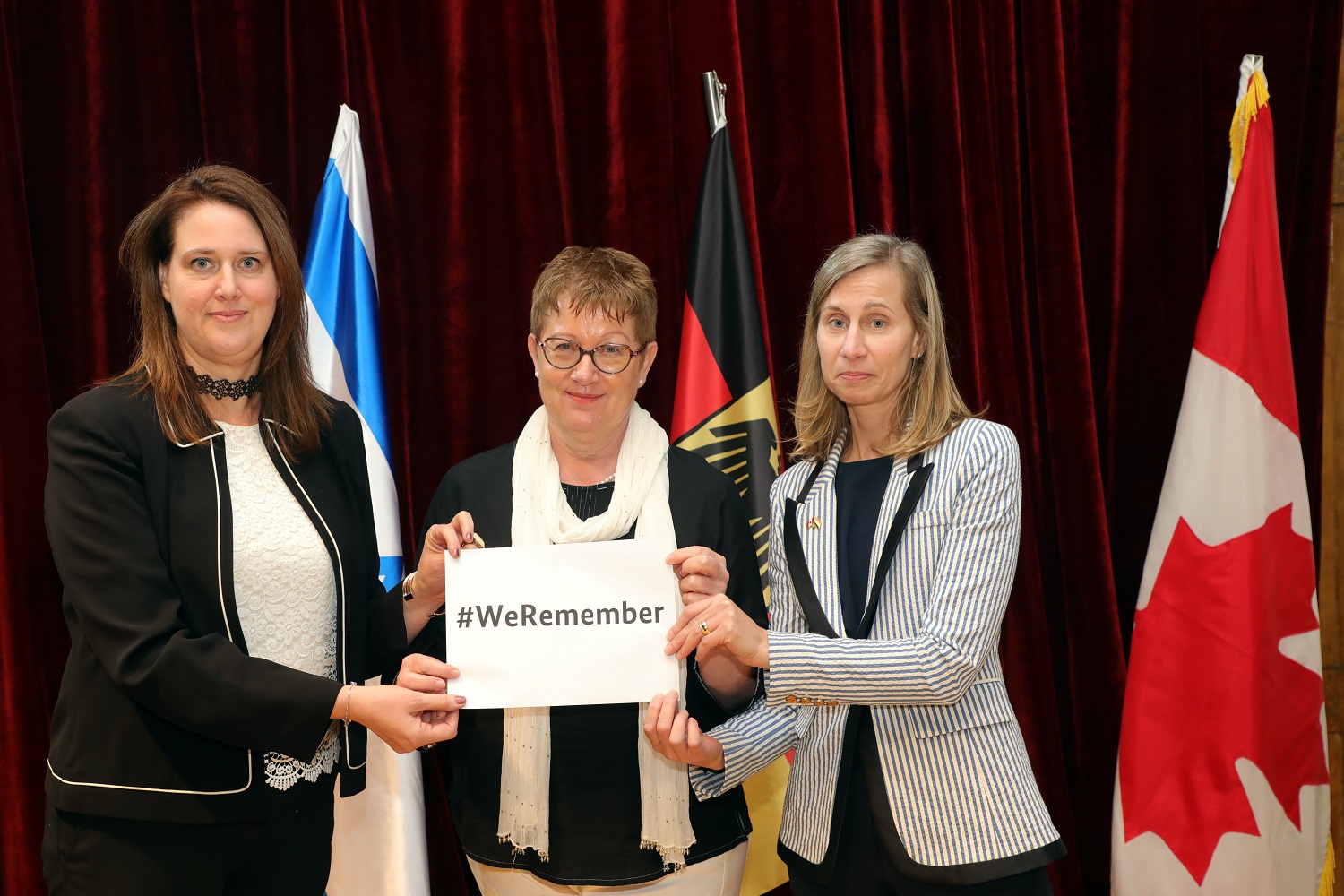 Ms. Dana Kursh, Consul General of Israel, Ms. Margit Hellwig-Boette, Consul General of Germany, and Ms. Nicole Girard, Consul General of Canada, with #WeRemember placard.